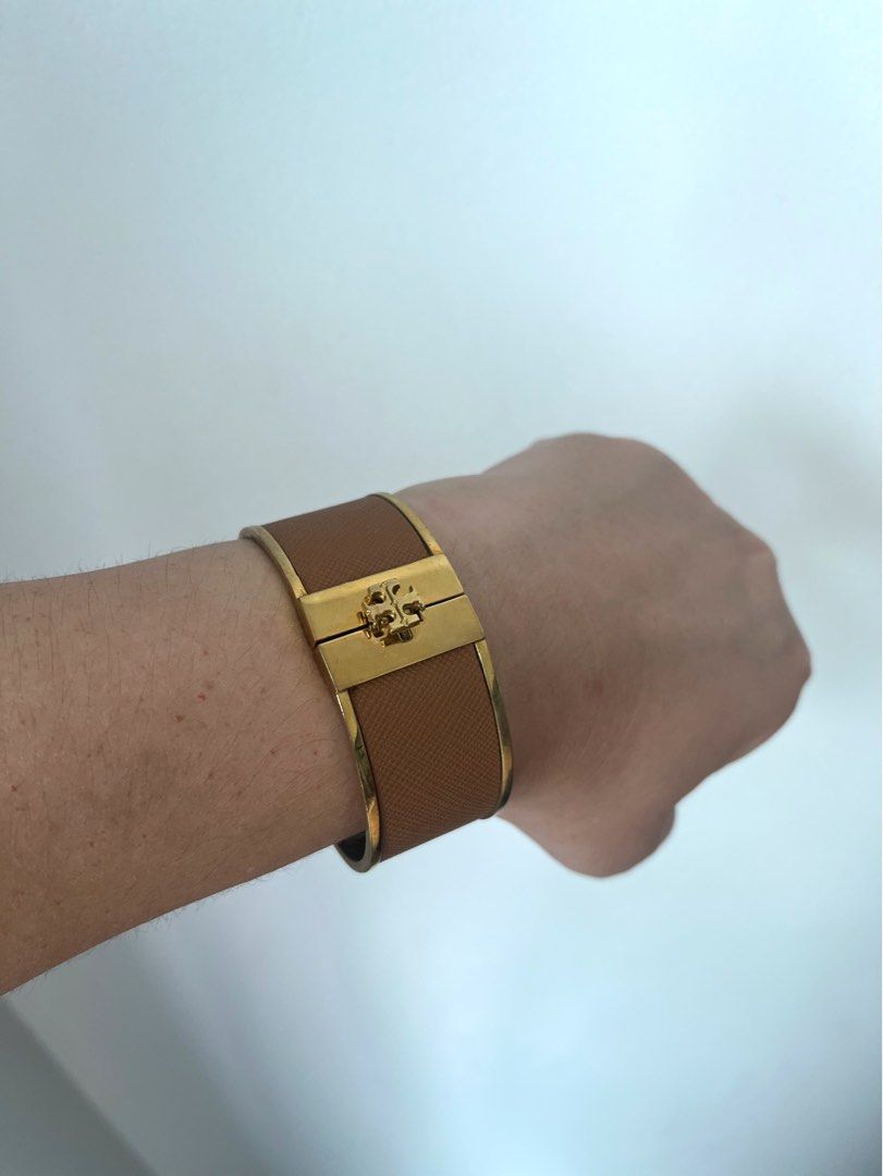 Tory Burch Gold and Tan Leather Logo Bangle (Category: Bracelets) located in Manila. Submitted by r.ruth (Listing ID 1446181578, Image 2). Description: - Authentic Tory Burch bangle - Gold-tone finish - Tan leather detailing - Features iconic Tory Burch logo - Secure hinged closure - Shows signs of wear on the inside metal, consistent with normal use - NOT FOR FUSSY BUYER .