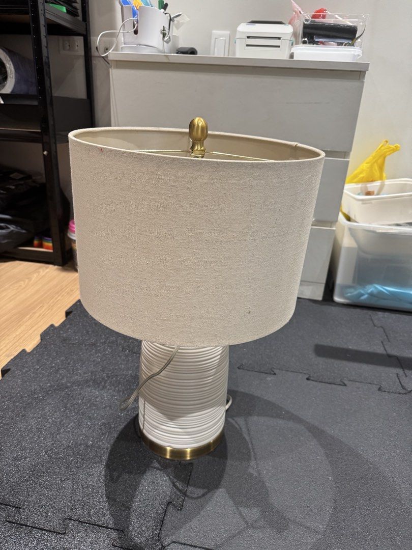 White Textured Ceramic Table Lamp with Beige Drum Shade (Category: Lighting) located in Quezon City. Submitted by slyn1234 (Listing ID 1446168977, Image 2). Description: - White ceramic table lamp - Textured, ribbed base - Subtle gold accent at the bottom - Neutral beige drum lampshade included - Provides a warm, inviting glow - Ideal for bedside tables or living room decor.