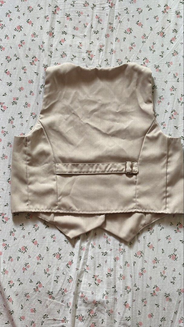 Beige V-Neck Button-Up Vest/ Waistcoat (Category: Sleeveless) located in Lucban. Submitted by ogchic (Listing ID 1446354537, Image 2). Description: - Beige V-neck vest - Closure: Single button at the front - Fit: Tailored with darts for a flattering silhouette - Details: Adjustable strap with buckle at the back - Style: Ideal for layering over tops or under blazers.