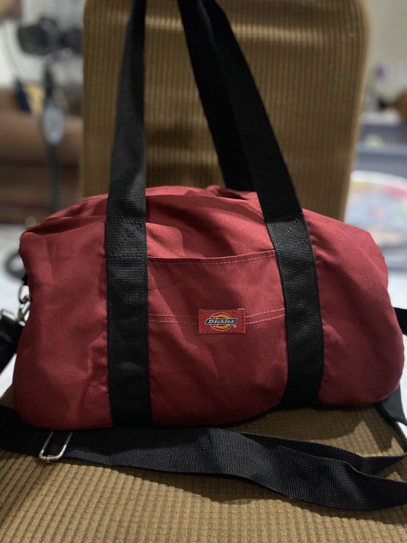 Dickies Red Duffle Bag with Shoulder Strap (Category: Sling Bags) located in Cadiz. Submitted by saveandstyleph (Listing ID 1446385102, Image 2). Description: - Red Dickies duffle bag - Features top handles and a detachable shoulder strap - Main compartment with zip closure - Includes a small front pocket - Perfect for gym sessions or weekend getaways - Made from durable material - Minor signs of use visible inside.