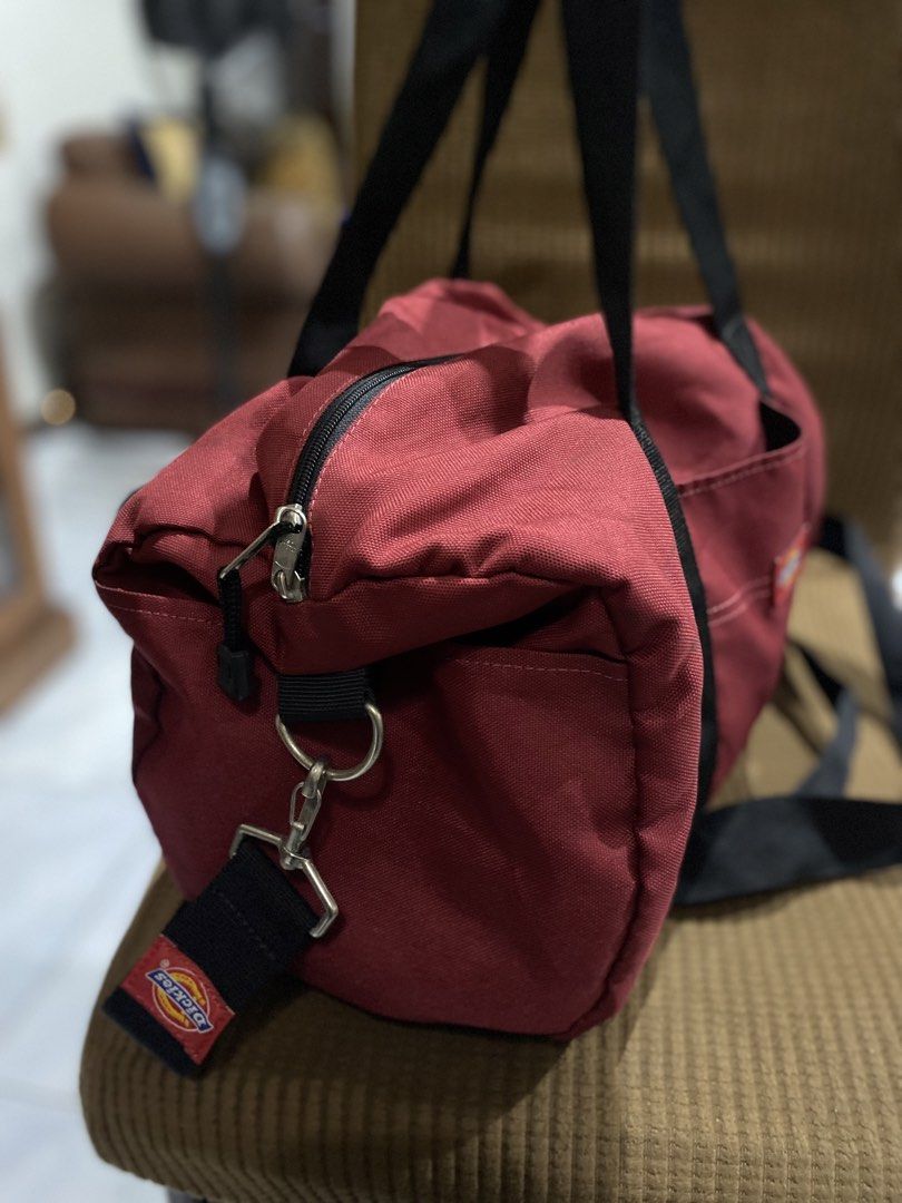 Dickies Red Duffle Bag with Shoulder Strap (Category: Sling Bags) located in Cadiz. Submitted by saveandstyleph (Listing ID 1446385102, Image 3). Description: - Red Dickies duffle bag - Features top handles and a detachable shoulder strap - Main compartment with zip closure - Includes a small front pocket - Perfect for gym sessions or weekend getaways - Made from durable material - Minor signs of use visible inside.