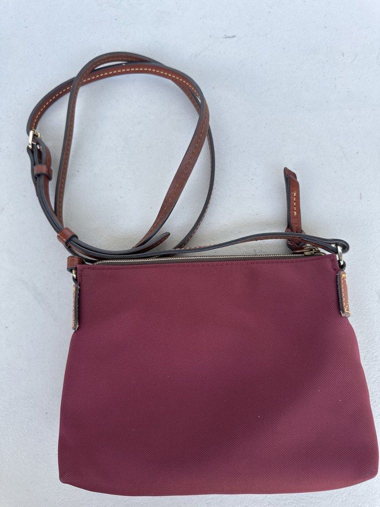 Dooney & Bourke Nylon Crossbody Pouchette (Category: Cross-body Bags) located in Manila. Submitted by classywardrobemanila (Listing ID 1446432571, Image 2). Description: Like new, just needs cleaning but all intact. Dooney & Bourke Nylon Crossbody Pouchette features a maroon nylon body and a stitched leather duck logo patch. Brand: Dooney & Bourke Material: Lightweight nylon with leather trim Features: Adjustable shoulder strap and a zip-top clos
