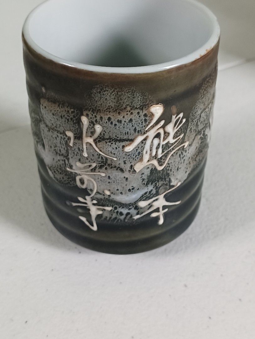 Japanese Ceramic Tea Cup with Kanji Writing (Category: Coffee & Tea Tableware) located in Manila. Submitted by iamwhilmz (Listing ID 1446355533, Image 2). Description: - Handcrafted ceramic tea cup - Unique textured glaze in dark brown and white - Decorated with traditional Japanese Kanji characters - Perfect for green tea or sake - Adds an authentic touch to your tea ceremony - Beautiful piece for collectors.