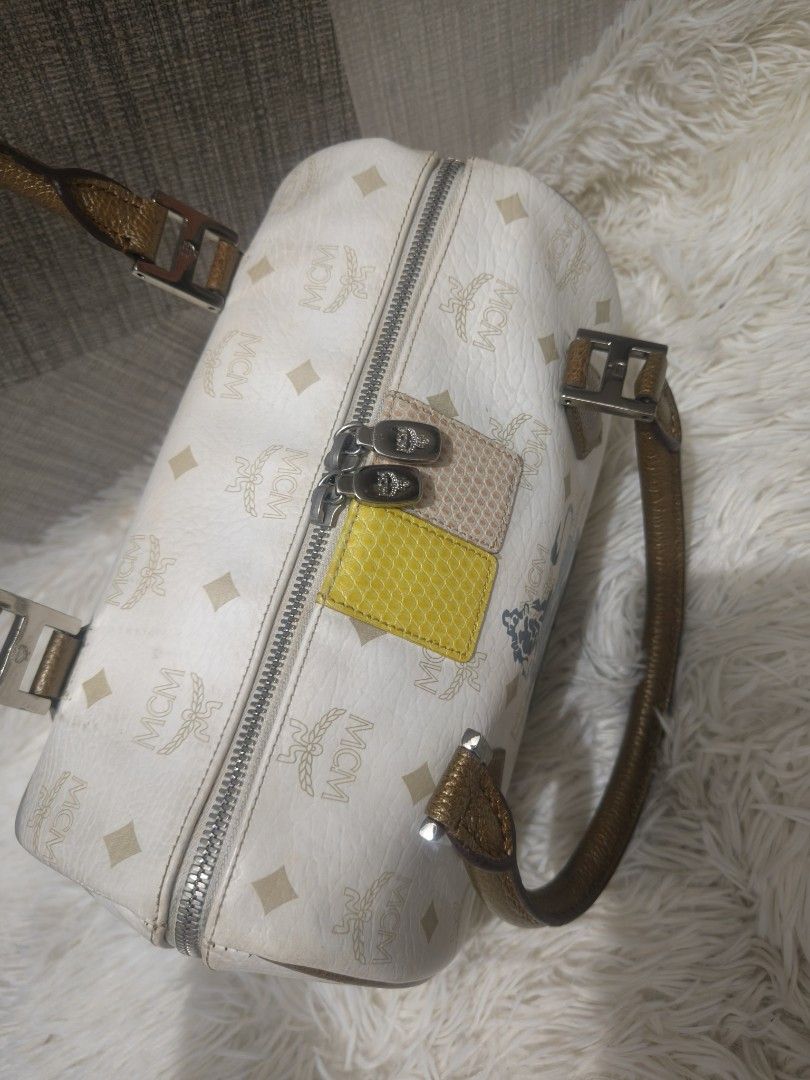 MCM Boston Bag with Lion Emblem (Category: Luxury Bags & Wallets) located in Imus. Submitted by desvasquez (Listing ID 1446398445, Image 3). Description: - MCM Boston bag - Iconic all-over MCM logo print - Unique lion emblem on the front - Stylish brown handles - Elegant gold-tone hardware - Two decorative colored patches (yellow & pink) on the front - Secure zipper closure - ykk zip -26 cm -minimal signs of use - no major issue.