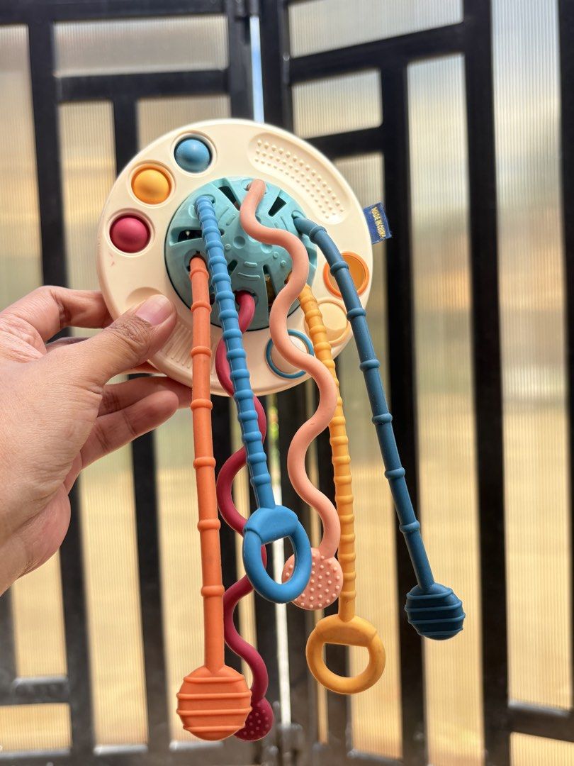 Montessori Sensory Pull String Toy for Babies (Category: Infant Playtime) located in Manila. Submitted by biboystoyhouse (Listing ID 1446441356, Image 1). Description: - Fun sensory toy for babies - Features colorful pull strings and textured surfaces - Excellent for developing fine motor skills - Encourages sensory exploration with engaging colors and textures - Designed for small hands to grasp and manipulate easily - Perfect travel companion f