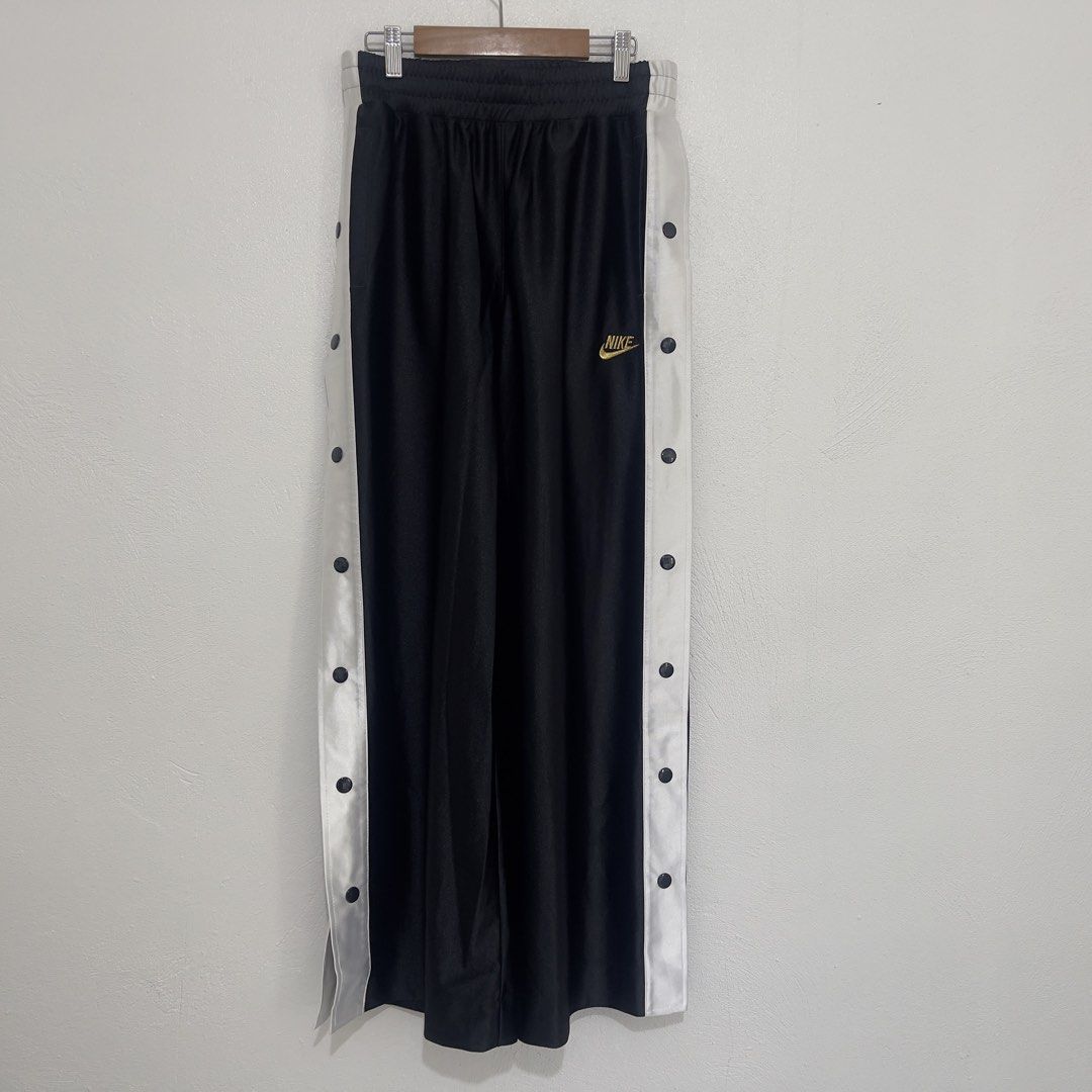 Nike Tearaway Track Pants Snap Button Black White Gold (Category: Other Bottoms) located in Manila. Submitted by 133.stor (Listing ID 1446375770, Image 1). Description: - Classic Nike tearaway track pants - Color: Black with white side panels - Full snap button closure down the sides - Gold Nike logo on the left leg - Elastic waistband with drawstring - Ideal for casual wear or sports.