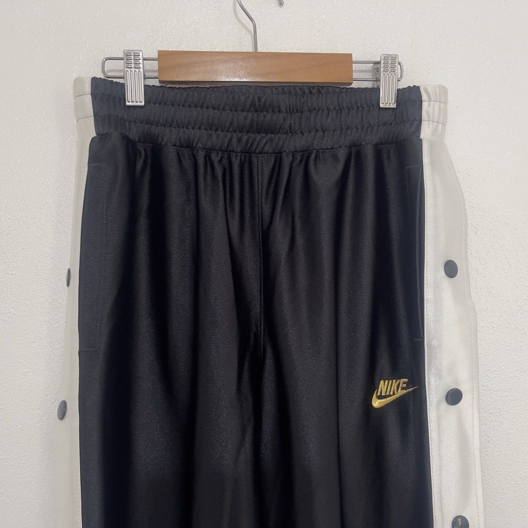 Nike Tearaway Track Pants Snap Button Black White Gold (Category: Other Bottoms) located in Manila. Submitted by 133.stor (Listing ID 1446375770, Image 2). Description: - Classic Nike tearaway track pants - Color: Black with white side panels - Full snap button closure down the sides - Gold Nike logo on the left leg - Elastic waistband with drawstring - Ideal for casual wear or sports.