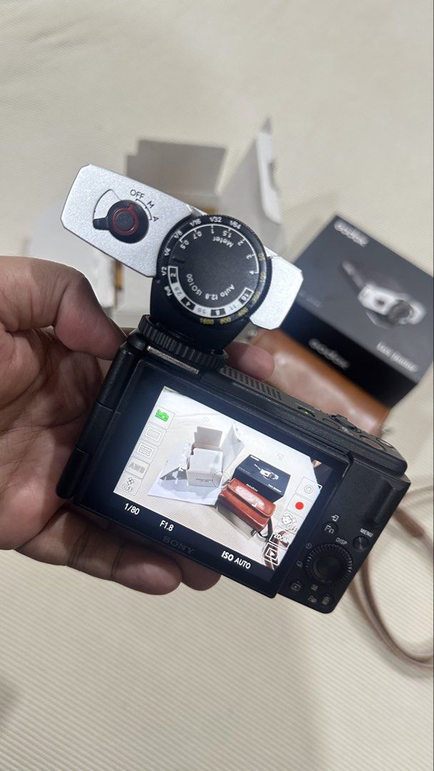 Sony ZV-1M2 Digital Camera with Godox Lux Junior Flash (Category: Cameras) located in Kuala Lumpur. Submitted by newhomeforme (Listing ID 1446470042, Image 2). Description: - Sony ZV-12M digital camera - Original box and manual included - Comes with a brown leather case - Includes a Godox Lux Junior flash - 64GB SanDisk memory card provided - Ideal for vlogging and photography.