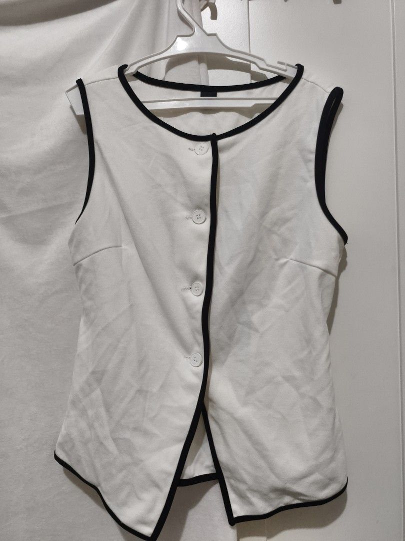 White Sleeveless Vest with Black Trim (Category: Sleeveless) located in Muntinlupa City. Submitted by cozmovingout (Listing ID 1446493047, Image 1). Description: - White sleeveless vest - Black trim on neckline and armholes - Three buttons down the front - Adjustable tie at the back for a custom fit - Smart casual style - Ideal for layering.