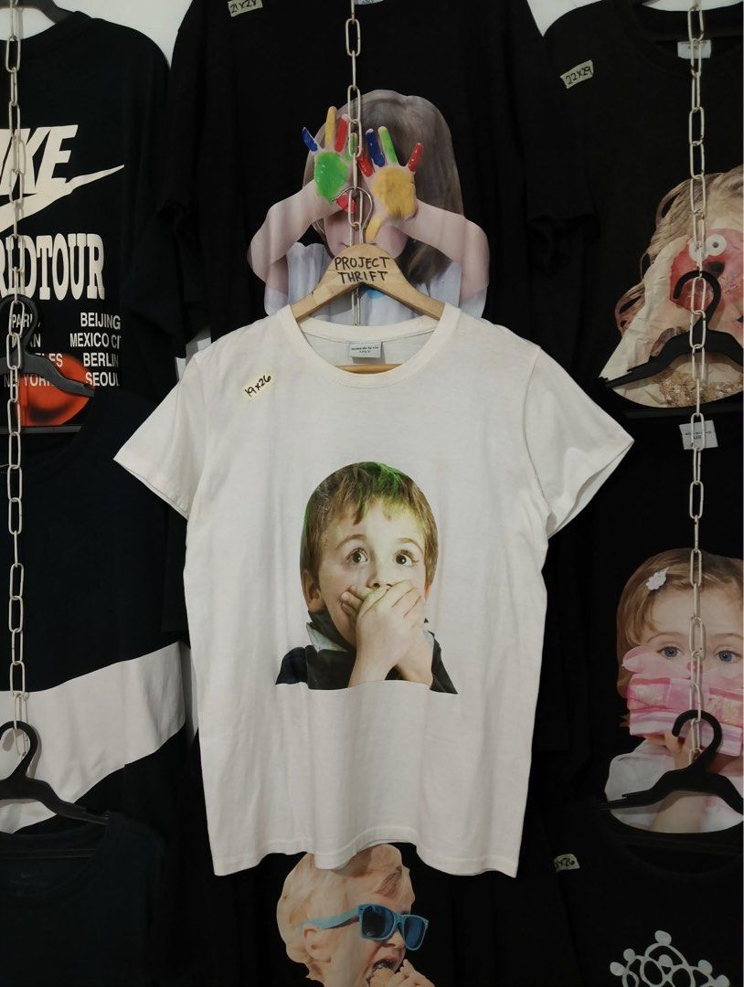 ADLV T-Shirt with Boy Print (Category: Tshirts & Polo Shirts ) located in Siniloan. Submitted by project_thrift (Listing ID 1446644581, Image 1). Description: - Classic white crew neck t-shirt - Features a vibrant and detailed graphic print of a young boy covering his mouth - Approximate measurements: 19 inches (width) x 26 inches (length) - Ideal for casual everyday wear.