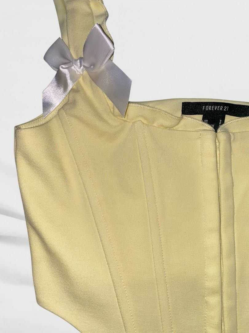 Forever 21 Yellow Corset Top with Bows (Category: Others Tops) located in Manila. Submitted by crescentmayari (Listing ID 1446690884, Image 2). Description: - Cute yellow corset top from Forever 21 - Zipper front closure - Hook-and-eye closure at the back - Adorable white ribbon bows on the straps - Versatile for dressing up or down - Fits size S.