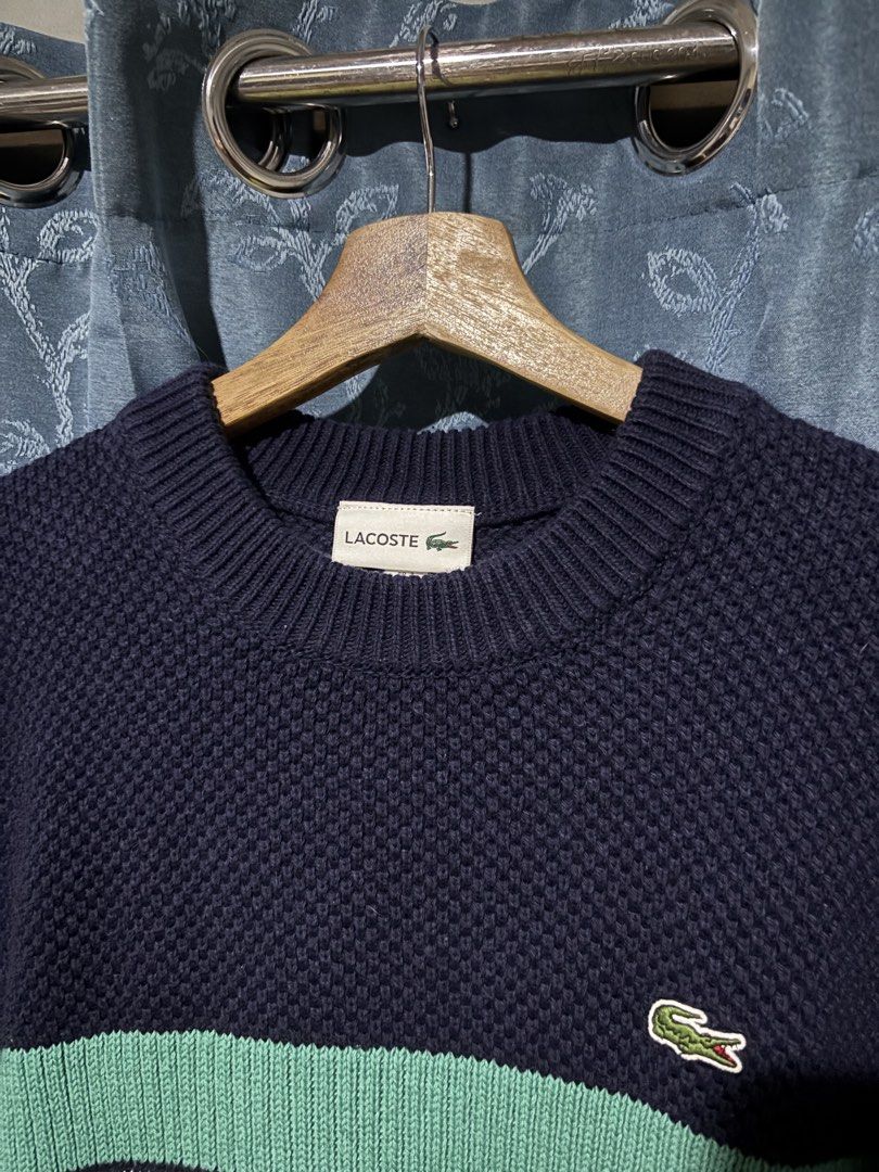 Lacoste Navy Blue Striped Knit Sweater (Category: Longsleeves) located in Cebu City. Submitted by somewhereintime_ (Listing ID 1446659652, Image 2). Description: - Navy blue Lacoste knit sweater - Features horizontal stripes in green and white across the chest - Classic crew neck design - Textured waffle-like knit pattern - Versatile for layering or standalone wear - Made in Japan.