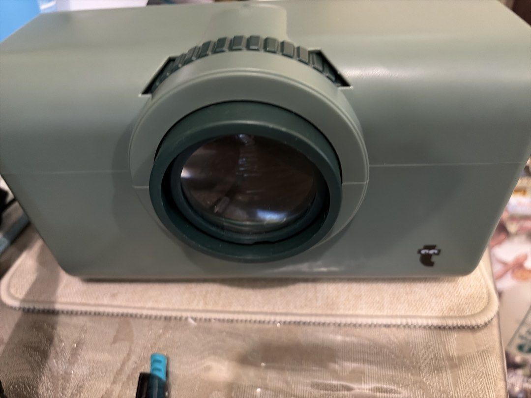 Vintage Grey Green Projector (Category: Projectors) located in Mandaluyong City. Submitted by iheartsokorpear (Listing ID 1446613602, Image 1). Description: - Old school projector - Light grey casing - Dark green lens surround - Ribbed focus wheel on top - Small logo on the side - Ideal for retro displays or as a prop.