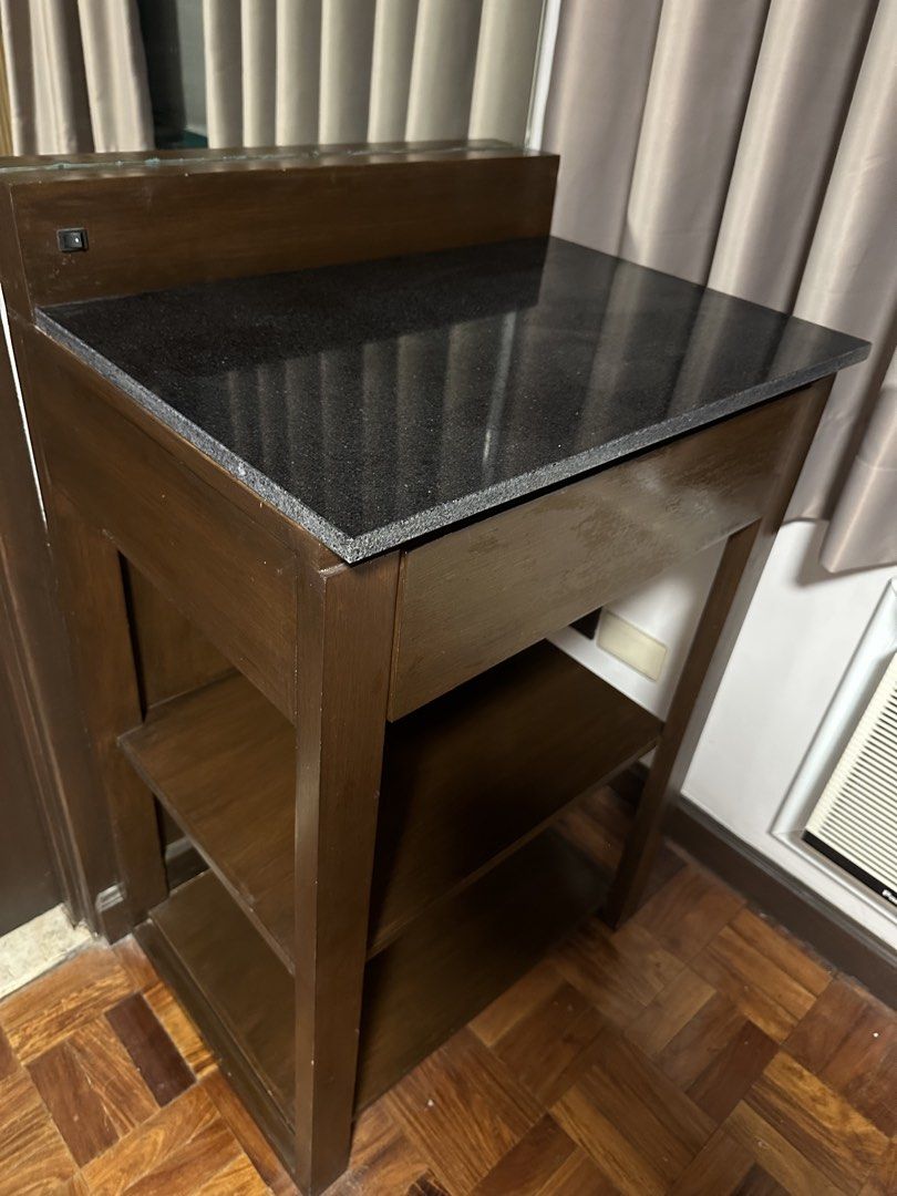 Wooden Vanity Table with Granite Top and Mirror (Category: Tables & Sets) located in Taguig. Submitted by kristeta85 (Listing ID 1446591433, Image 2). Description: - Compact wooden vanity table - Features a dark granite top - Two open shelves for storage - Includes a mirror above the top - Pull-out drawer for additional storage - Ideal for small spaces - 60cm W x 47cm D x 90cm H of table - 193cm H total height with mirror - RFS: Redecorating - Pi