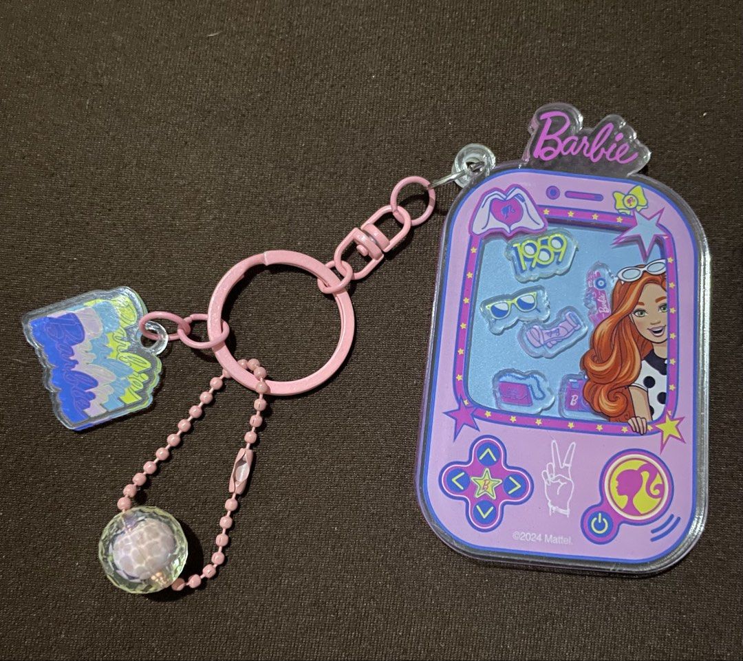 Barbie Keychain & Mini Doll Set (Category: Kids Toys) located in Plaridel. Submitted by julien_stuff (Listing ID 1441711885, Image 2). Description: RFS: Outgrown them already; need funds - Adorable Barbie keychain featuring a retro game console design. - Includes fun, eye-catching charms. - Comes with a mini Barbie doll dressed in a vibrant outfit. - Doll is presented on a stylish pink base. - Ideal for Barbie collectors and enthusiasts..