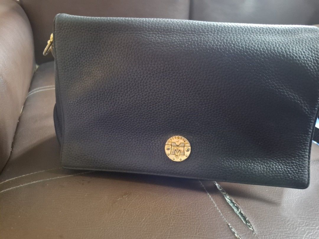 Black leather shoulder bag with gold emblem (Category: Clutches) located in Taguig. Submitted by jcstjg (Listing ID 1441632186, Image 1). Description: - Sleek black leather flap bag - Elegant gold emblem on the front - Secure front magnetic closure - Ideal size for essentials - Perfect for nights out or special occasions. Medium size. with small pocket inside and at the back.