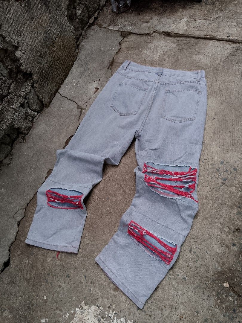 Custom Ripped Light Wash Jeans with Red Thread Detail (Category: Jeans) located in Muntinlupa City. Submitted by jo_thrift2 (Listing ID 1441763131, Image 2). Description: - Light wash denim jeans - Custom ripped and distressed look - Unique red thread woven through rips for a pop of color - Statement piece for edgy streetwear style - Close-up photos available to show intricate details.