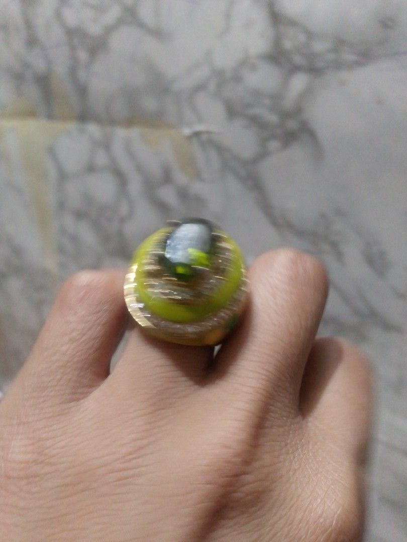 Gold Tone Ring with Green Stone and Crystals (Category: Rings) located in Manila. Submitted by epicwind_1bf746 (Listing ID 1441764095, Image 2). Description: - Eye-catching statement ring - Large green center stone - Surrounded by sparkling clear crystals - Gold-toned band with unique yellow enamel detail - Shows some signs of wear on the band.