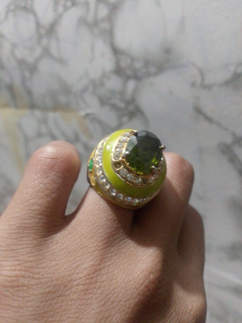 Gold Tone Ring with Green Stone and Crystals (Category: Rings) located in Manila. Submitted by epicwind_1bf746 (Listing ID 1441764095, Image 3). Description: - Eye-catching statement ring - Large green center stone - Surrounded by sparkling clear crystals - Gold-toned band with unique yellow enamel detail - Shows some signs of wear on the band.