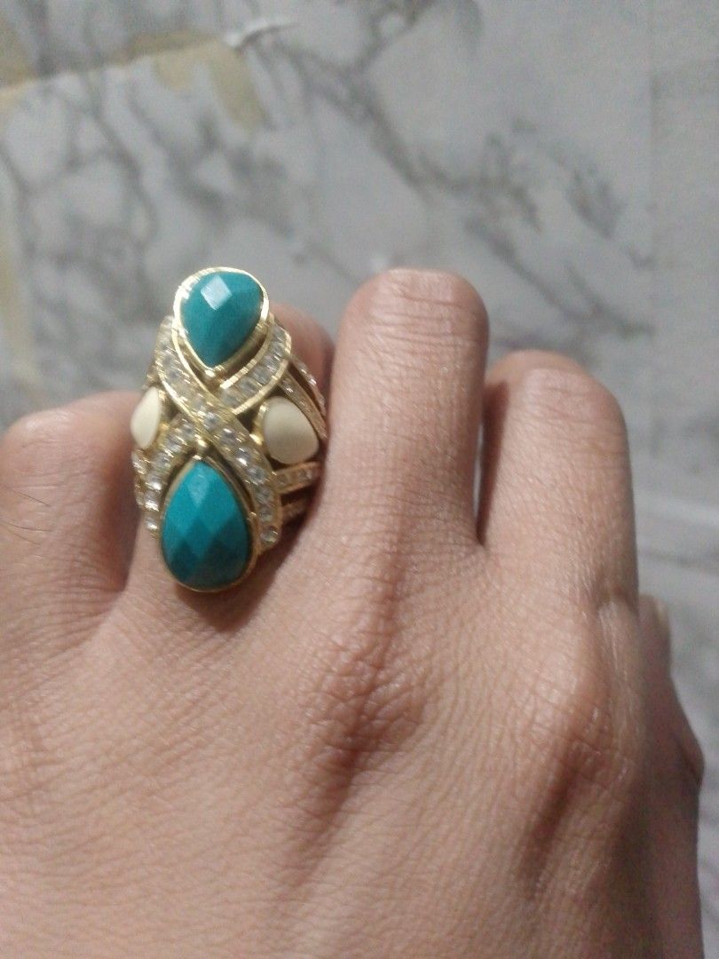 Gold Tone Statement Ring with Turquoise and White Stones (Category: Rings) located in Manila. Submitted by epicwind_1bf746 (Listing ID 1441764002, Image 1). Description: - Bold statement ring - Gold-tone metal base - Features two large teardrop turquoise stones - Accented with smaller white stones - Unique criss-cross band pattern - Perfect for adding a pop of color to any outfit.