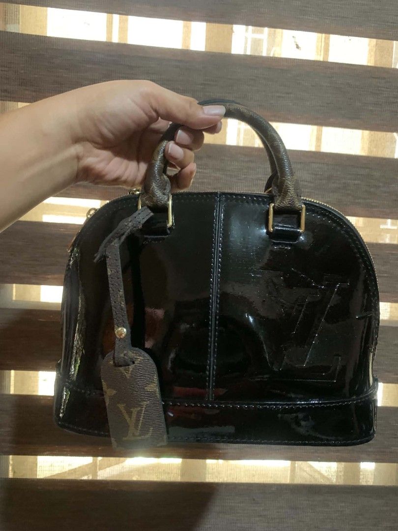 Louis Vuitton Monogram Vernis Alma BB Black (Category: Luxury Bags & Wallets) located in Aliaga. Submitted by akishaoshop2010. (Listing ID 1441711562, Image 1). Description: - Classic Louis Vuitton Alma BB bag - Black patent leather with signature monogram - Gold hardware and zipper - Includes a leather tag - Handles show some wear - Ideal for everyday use.