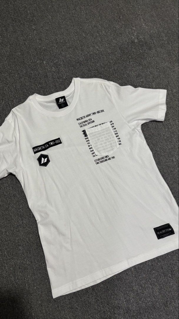 Macbeth Army Tactical Division White T-Shirt (Category: Tshirts & Polo Shirts ) located in Manila. Submitted by pastlovd (Listing ID 1441658585, Image 1). Description: - White Macbeth t-shirt - Size: Large (L) - Features 'Macbeth Army Two-002 Div.' and 'California USA Tactical Division' graphics - Includes a pocket detail with text - Ideal for casual wear - Complete tags, Necktag and Washtag - Condition: Flawless - 27.5 x 19.5 .