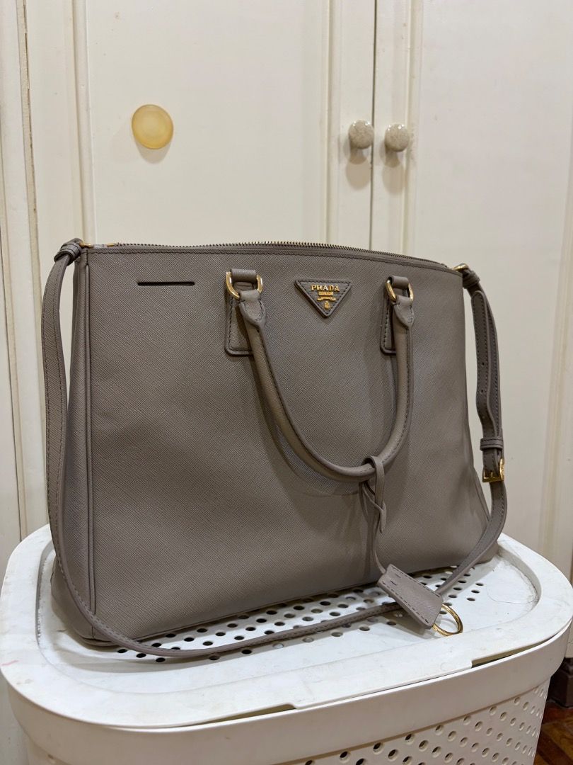 Prada Saffiano Lux Tote Bag Grey (Category: Luxury Bags & Wallets) located in Pasig City. Submitted by angelaboo__ (Listing ID 1441741195, Image 1). Description: - Material: Grey Saffiano Leather - Hardware: Gold - Features: Detachable shoulder strap, multiple interior compartments - Ideal for: Work or everyday use - Message for more details PRELOVED BAGS with minor stains/issues - can be washed off Prada - Saffiano Lux Tote in gray hard leather,