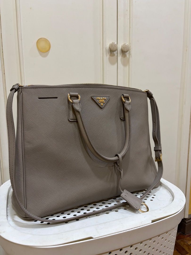 Prada Saffiano Lux Tote Bag Grey (Category: Luxury Bags & Wallets) located in Pasig City. Submitted by angelaboo__ (Listing ID 1441741195, Image 2). Description: - Material: Grey Saffiano Leather - Hardware: Gold - Features: Detachable shoulder strap, multiple interior compartments - Ideal for: Work or everyday use - Message for more details PRELOVED BAGS with minor stains/issues - can be washed off Prada - Saffiano Lux Tote in gray hard leather,