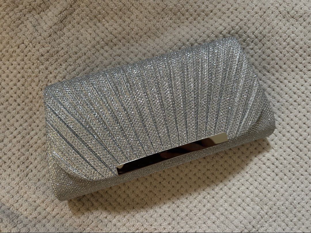Silver Glitter Pleated Clutch Bag with Chain Strap (Category: Clutches) located in Manila. Submitted by matchaberrylauverr (Listing ID 1441694346, Image 1). Description: - Sparkly silver clutch bag - Elegant pleated design - Secure metallic clasp closure - Detachable long silver chain strap - Ideal for parties & special occasions - Dimensions: 8" wide x 4" tall - Fits essentials: phone, keys, lipstick.