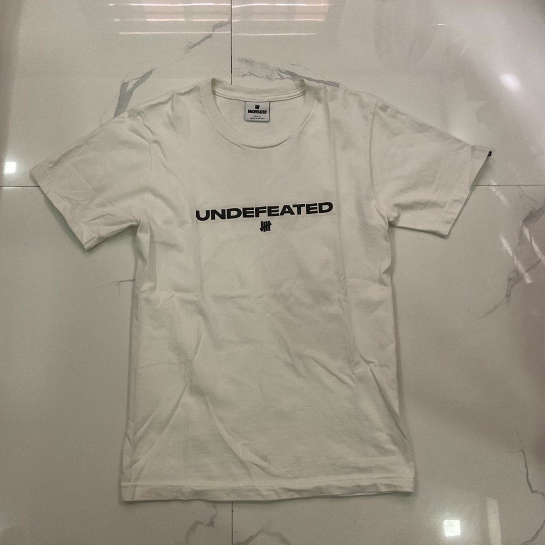 Undefeated White T-Shirt Size Small (Category: Tshirts & Polo Shirts ) located in Manila. Submitted by okeanos (Listing ID 1441773955, Image 1). Description: - Authentic Undefeated White T-Shirt - Size: Small - Features the iconic Undefeated logo prominently on the chest - Subtle Undefeated logo detail on the sleeve - Proudly made in Mexico - Ideal for casual and everyday wear.