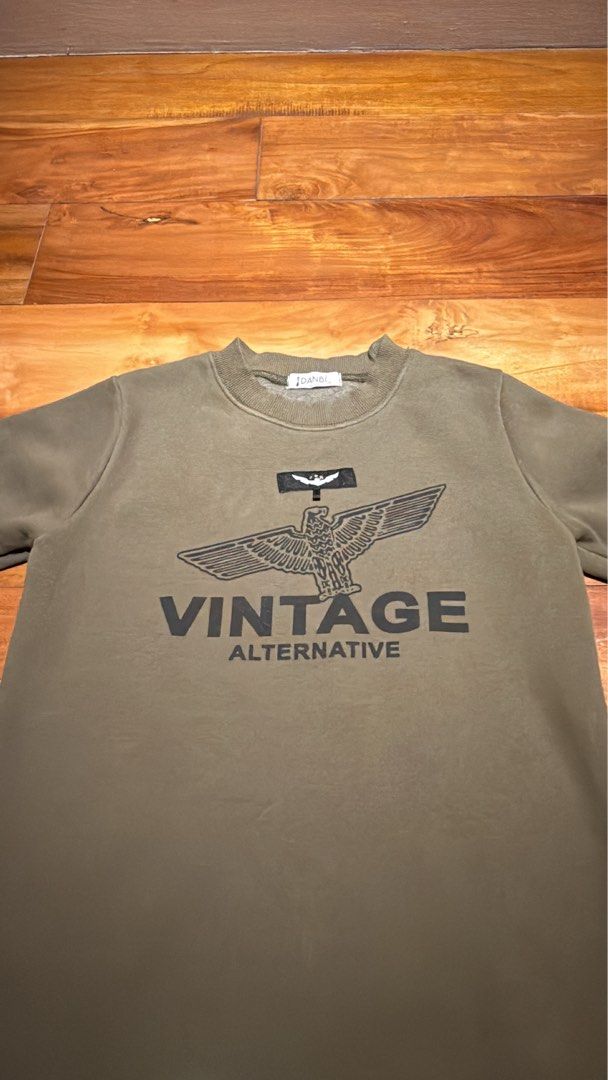 Vintage Alternative Eagle Graphic Crewneck Sweatshirt (Category: Babies & Kids Fashion) located in Pateros City. Submitted by eunikaesp92479 (Listing ID 1441752247, Image 3). Description: - Olive green crewneck sweatshirt - Features a black eagle graphic with 'VINTAGE ALTERNATIVE' text - Long sleeves with ribbed cuffs and hem - Classic and simple design - Ideal for casual wear.