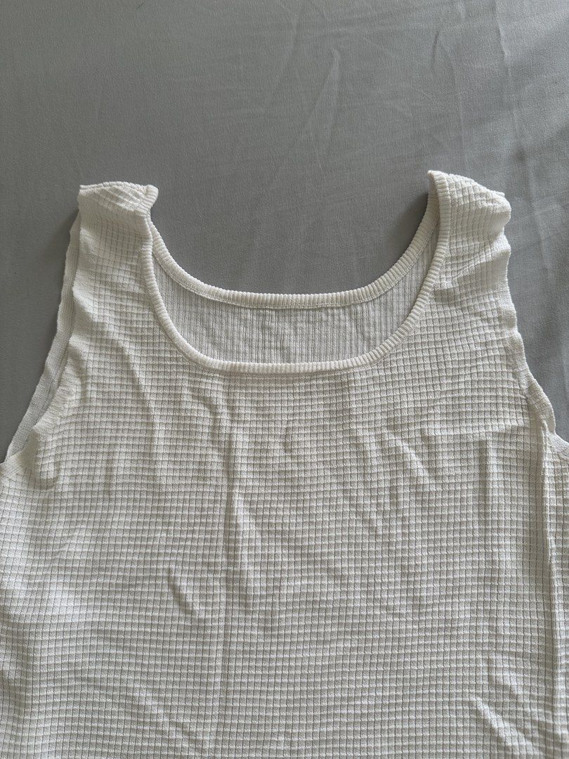 White Waffle Knit Tank Top (Category: Sleeveless) located in Paranaque City. Submitted by declutterwyae (Listing ID 1441625380, Image 2). Description: - Basic white tank top - Waffle knit texture for a subtle detail - Sleeveless design - Flattering scoop neckline - Versatile piece: great for layering or wearing on its own - Effortlessly pairs with any bottoms - Comfortable fabric for all-day wear.