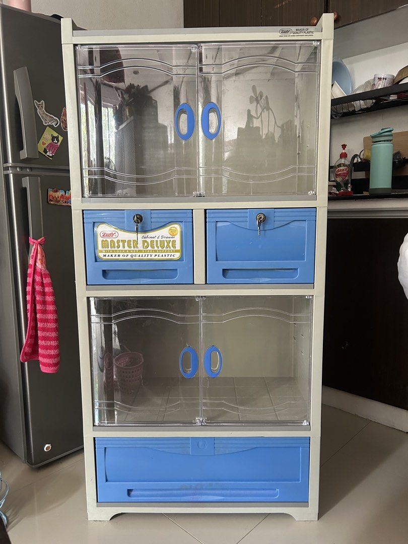Zooey Master Deluxe Plastic Cabinet with Drawers (Category: Shelves, Cabinets & Racks) located in Manila. Submitted by love.preibae (Listing ID 1441618608, Image 1). Description: - Durable plastic storage cabinet. - Clear doors with stylish blue handles. - Multiple shelves and drawers for ample storage. - Two drawers include built-in locks for added security. - Easy to clean and lightweight for convenient moving. - Ideal solution for organizing v