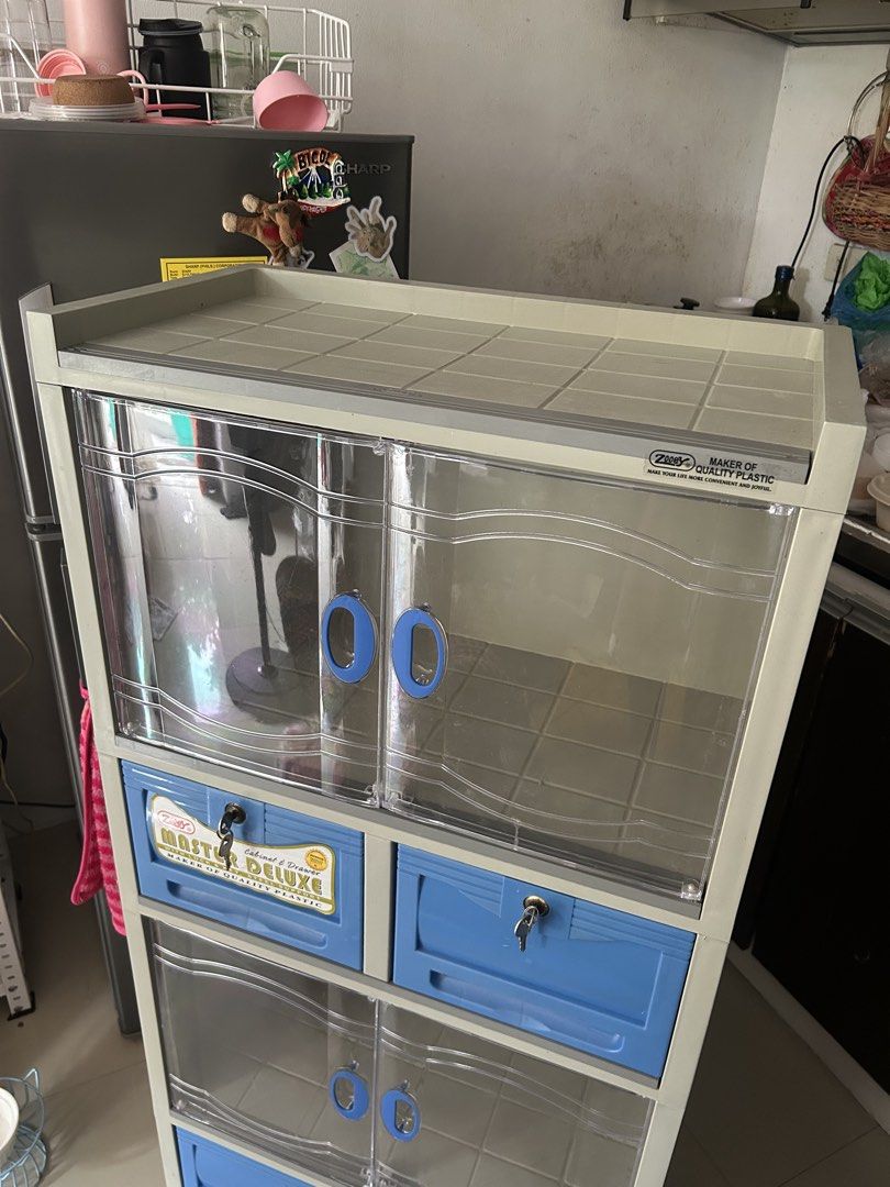 Zooey Master Deluxe Plastic Cabinet with Drawers (Category: Shelves, Cabinets & Racks) located in Manila. Submitted by love.preibae (Listing ID 1441618608, Image 2). Description: - Durable plastic storage cabinet. - Clear doors with stylish blue handles. - Multiple shelves and drawers for ample storage. - Two drawers include built-in locks for added security. - Easy to clean and lightweight for convenient moving. - Ideal solution for organizing v