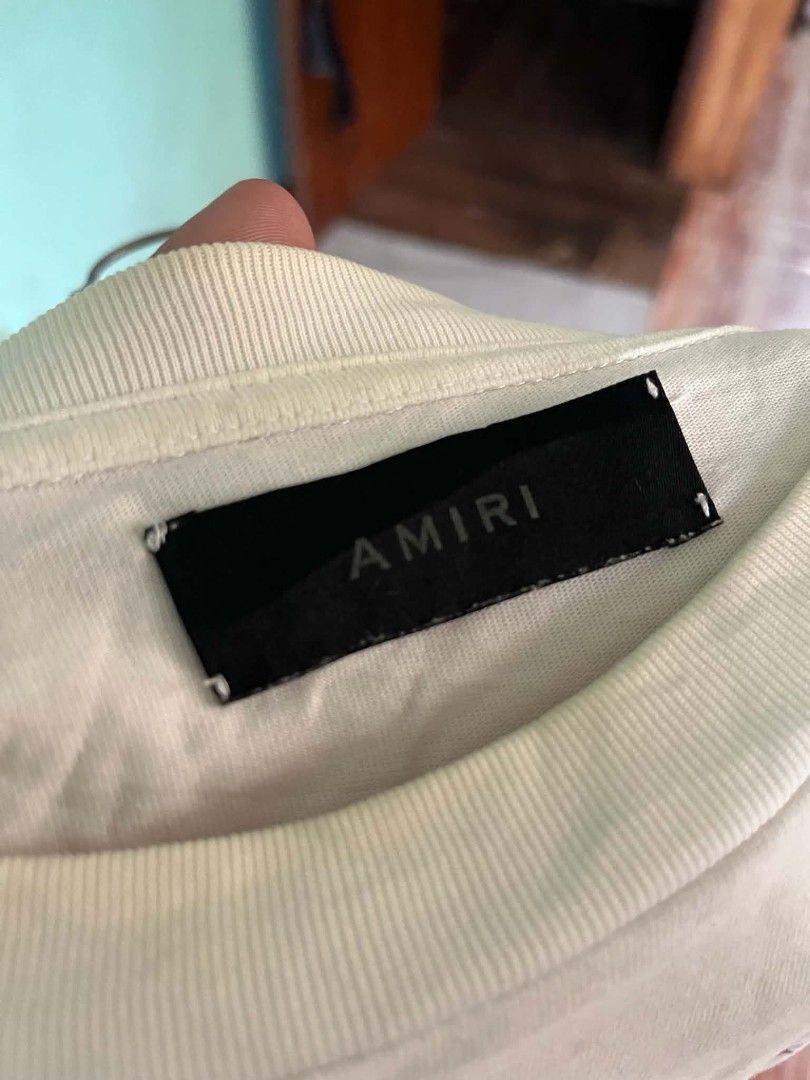AMIRI White Drip Graphic T-Shirt (Category: Tshirts & Polo Shirts ) located in Andop. Submitted by chinithou (Listing ID 1446798335, Image 3). Description: - Authentic AMIRI T-shirt - Color: White - Size: L - Design: Drip graphic on front and back, AMIRI logo - Origin: Made in USA - Condition: Good, with minor signs of wear.