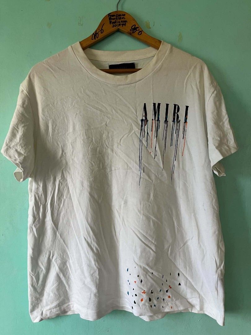 AMIRI White Drip Graphic T-Shirt (Category: Tshirts & Polo Shirts ) located in Andop. Submitted by chinithou (Listing ID 1446798335, Image 1). Description: - Authentic AMIRI T-shirt - Color: White - Size: L - Design: Drip graphic on front and back, AMIRI logo - Origin: Made in USA - Condition: Good, with minor signs of wear.