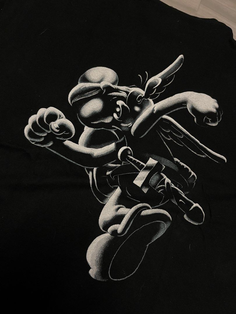 Black T-shirt with Asterix Graphic Print (Category: Tshirts & Polo Shirts ) located in Quezon City. Submitted by eronggi (Listing ID 1446818502, Image 3). Description: - Vintage 90s black t-shirt - Features a cool Asterix graphic print on both front and back - Made of comfortable fabric - Classic casual wardrobe essential - Perfect for fans of the Asterix comic series.