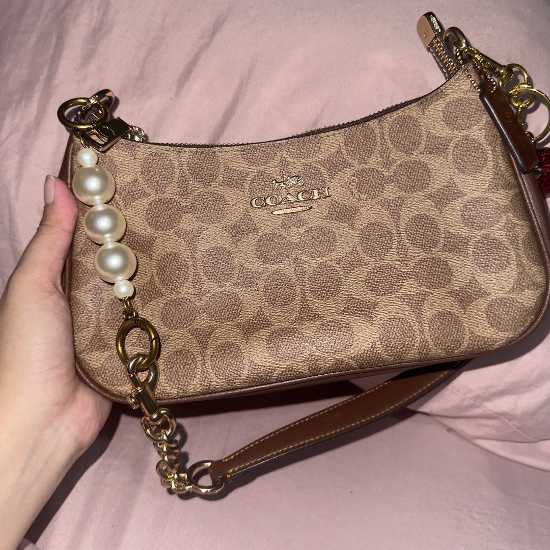 Coach Teri Shoulder Bag (Category: Luxury Bags & Wallets) located in Paranaque City. Submitted by c.c_preloved (Listing ID 1446838837, Image 1). Description: ORIGINAL COACH Teri in Gold Tan Brown No issues Used once RFS: need funds 💔 - Authentic Coach monogram mini shoulder bag - Classic brown and tan colorway - Elegant gold hardware details - Secure zipper closure - Convenient small wrist strap - Comes with a stylish pearl and chain charm - Inc