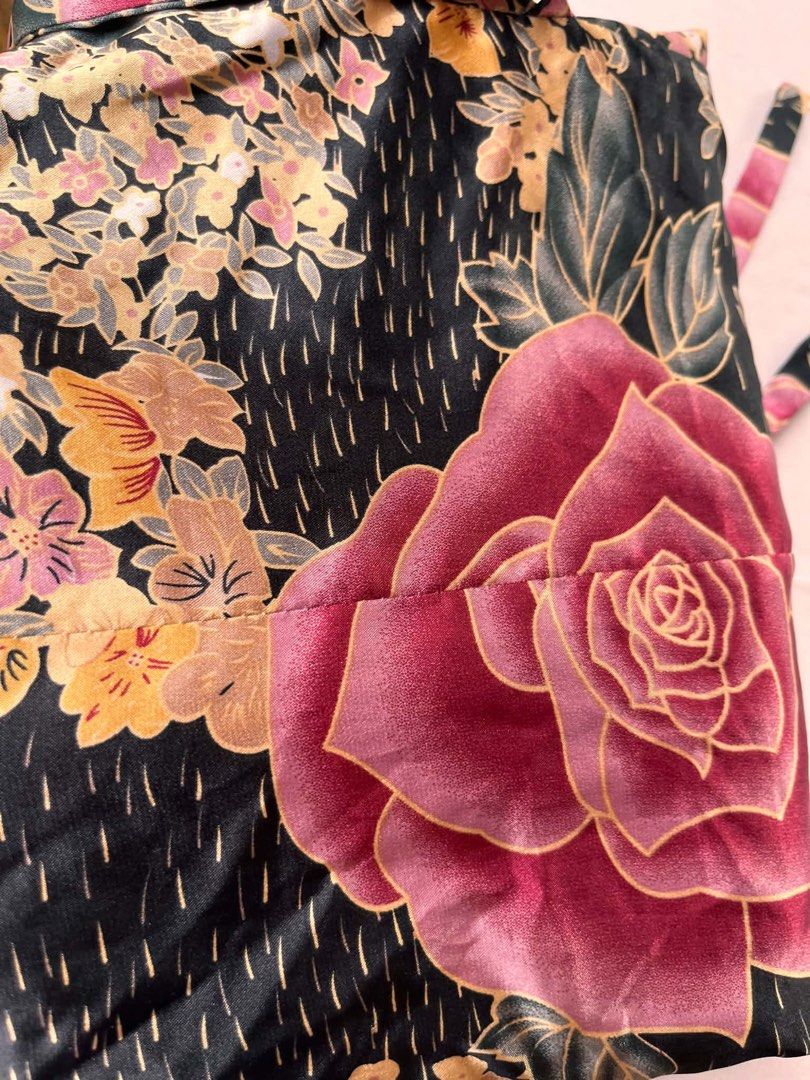 Floral Wrap Blouse with Tie Detail (Category: Blouses) located in Iloilo. Submitted by wanderzee (Listing ID 1446730812, Image 3). Description: - Elegant black blouse with a striking floral print. - Features prominent pink roses and delicate yellow and pink flowers. - Long sleeves for a sophisticated look. - Flattering wrap style with an adjustable side tie. - Fabric boasts a subtle, luxurious sheen. - Versatile piece: dress it up for events or d