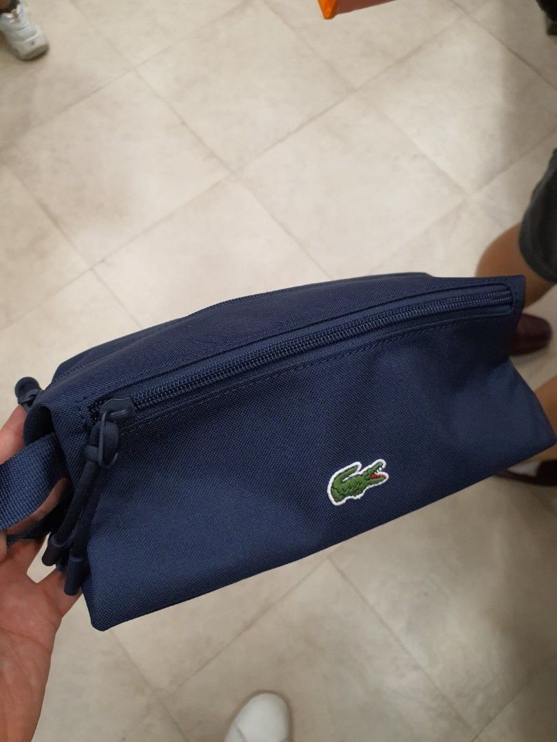 Lacoste Navy Blue Pouch Bag (Category: Luxury Bags & Wallets) located in Manila. Submitted by dominic000 (Listing ID 1446758276, Image 3). Description: Navy blue pouch from Lacoste. Has a main zippered compartment and a front zippered pocket. The material looks durable and water-resistant. Has a small handle on the side. Great for toiletries or small essentials. Measures about 9 inches long. PROMO!!!! brand new, original, not fake. never been use