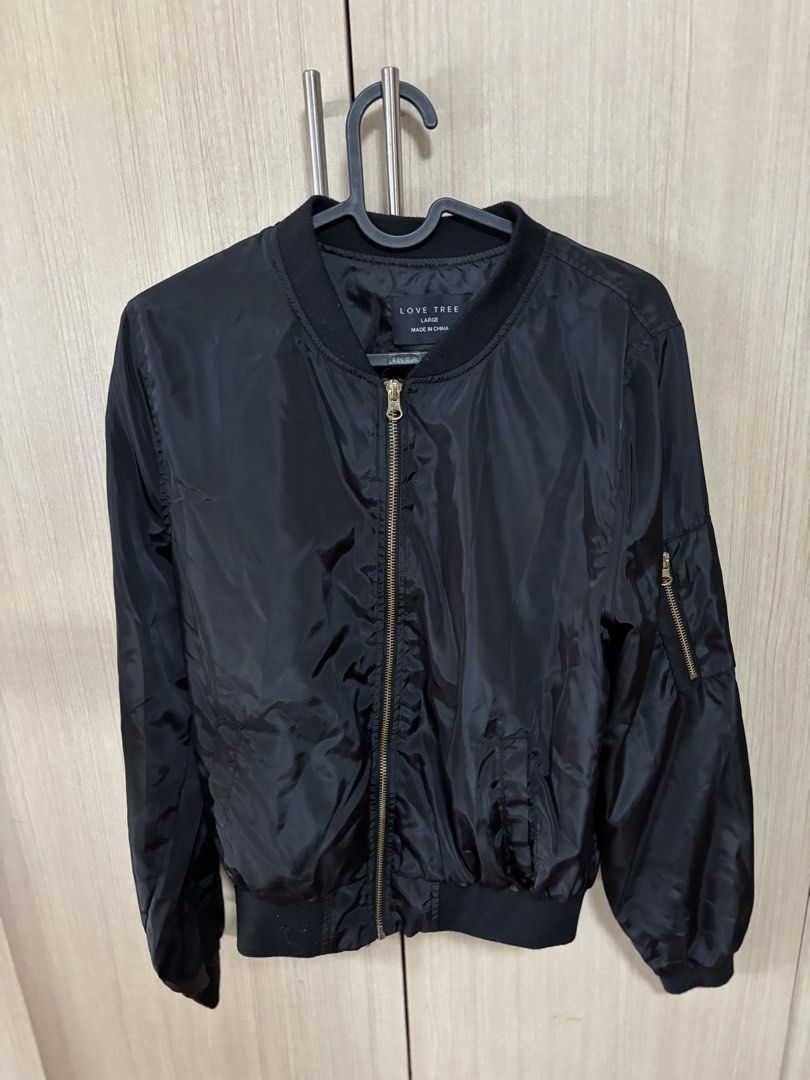 Love Tree Black Bomber Jacket - Size Large (Category: Coats, Jackets and Outerwear) located in Pasig City. Submitted by nina.declutter (Listing ID 1446844899, Image 1). Description: - Brand: Love Tree - Item: Black Bomber Jacket - Size: Large - Style: Classic bomber with zip-up front - Features: Zippered pocket on sleeve, ribbed collar, cuffs, and hem - Versatility: Perfect for layering or wearing solo, pairs easily with any outfit.