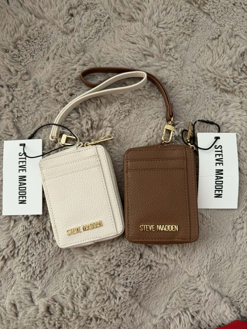 Steve Madden Cardholder Set with Lanyard (Category: Wallets & Card holders) located in San Leonardo. Submitted by arni0179 (Listing ID 1446850724, Image 1). Description: - Two Steve Madden cardholders: one cream, one brown. - Features a clear ID window on one side. - Multiple card slots on the other side. - Includes a detachable lanyard strap for convenience. - Elegant gold hardware details. - Ideal for organizing and easily accessing your essent