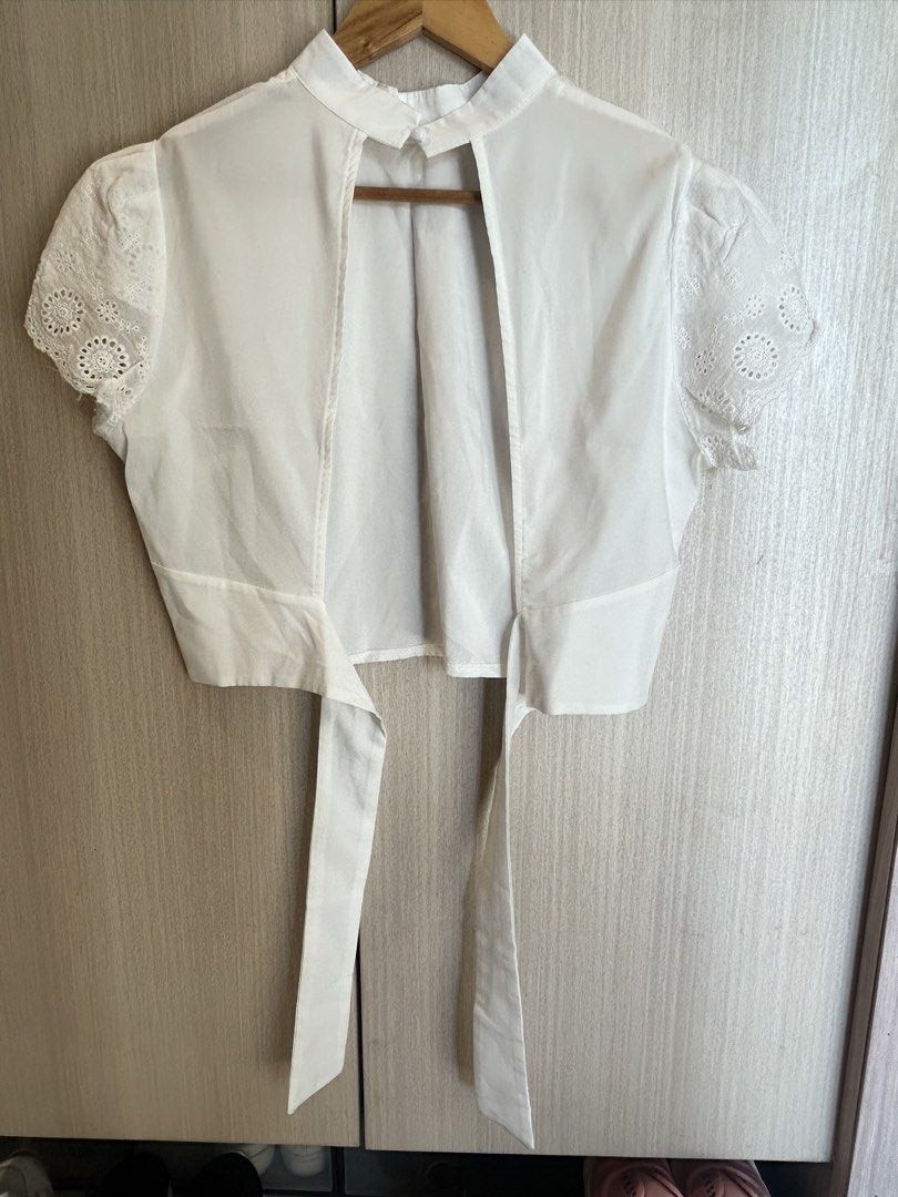 White Cropped Tie-Back Top with Eyelet Sleeves (Category: Blouses) located in Cainta. Submitted by kayeshoppe (Listing ID 1446742384, Image 2). Description: - White cropped top - High neckline - Short puff sleeves with eyelet details - Open back with tie closure - Versatile, pairs well with high-waisted bottoms - Simple and chic design.