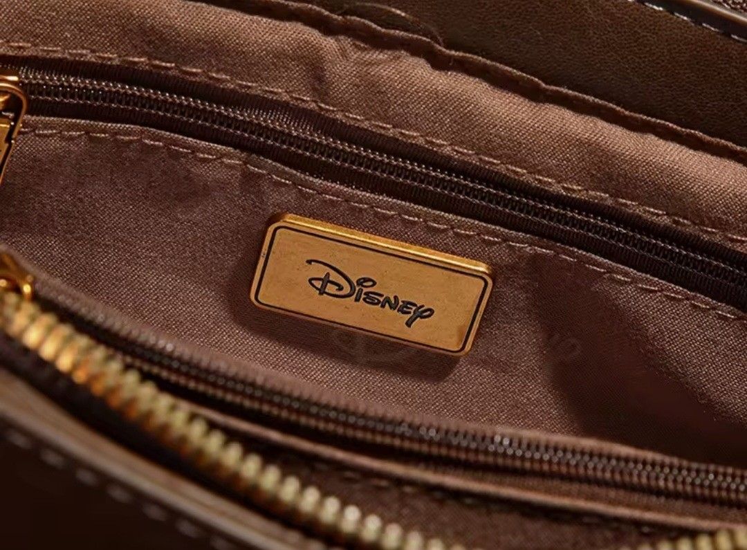 Brown Disney Mickey Mouse Crossbody Bag (Category: Cross-body Bags) located in Quezon City. Submitted by mimil_ (Listing ID 1441790493, Image 1). Description: - Cute brown crossbody bag - Features a Mickey Mouse clasp and "Mickey" charm - Comes with a stylish patterned strap - Perfect for everyday use or a fun Disney trip - Small and compact, ideal for carrying essentials - Detailed stitching on the flap -Bought at Laz*da Mall Disney Fashion Stor