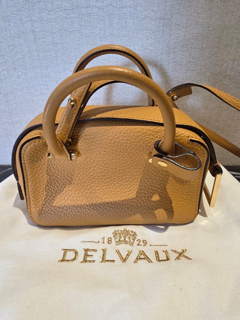 Delvaux Coolbox Nano Authentic (Category: Luxury Bags & Wallets) located in Pasig City. Submitted by vthing (Listing ID 1441817712, Image 2). Description: Color: Honey Condition: Excellent pre-loved condition with minimal signs of use. Leather remains supple and structured, with clean interiors and well-maintained hardware. Includes: • Original Delvaux dust bag • Removable shoulder strap A chic and understated luxury handbag that is increasingly 