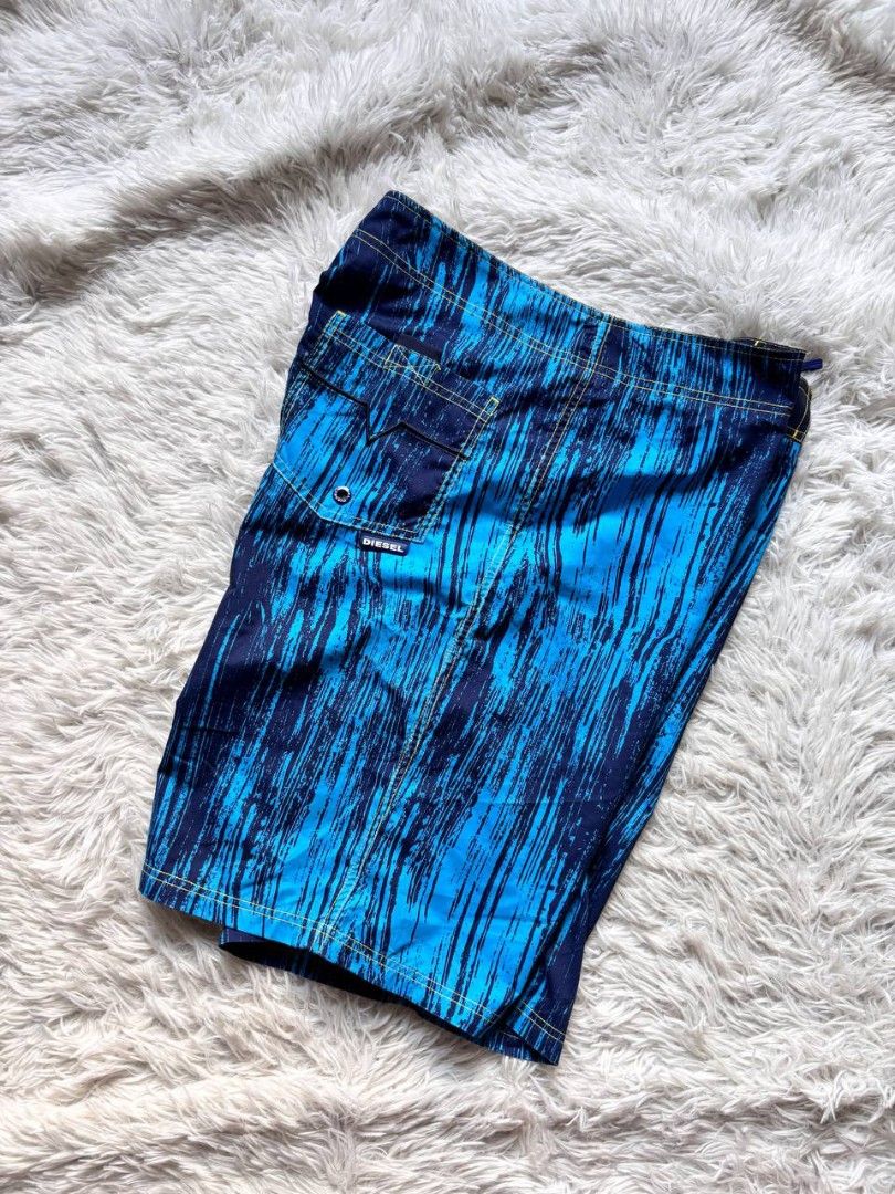 Diesel Board Shorts Blue Abstract Print (Category: Shorts) located in Catbalogan. Submitted by kristinapi (Listing ID 1441818976, Image 1). Description: - Brand: Diesel - Size: XL - Color/Print: Cool blue abstract print - Features: Drawstring waist, velcro fly, back pocket with button closure - Interior: Mesh lining - Ideal for: Swimming, pool lounging.
