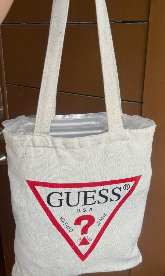 Guess USA Canvas Tote Bag (Category: Tote Bags) located in Paranaque City. Submitted by lyn0618 (Listing ID 1441882198, Image 3). Description: FOR SALE! GUARANTEED AUTHENTIC ! WHITE GUESS TAG INTACT inside SEE PHOTO PROOF it’s ORIGINAL GUESS. NOT COPY. - AUTHENTIC Classic Guess tote bag - Cream canvas with iconic red triangle logo - Small inner pocket with Guess Los Angeles tag - Great for everyday use - Easy to carry PRE LOVED. used. With CARE. 