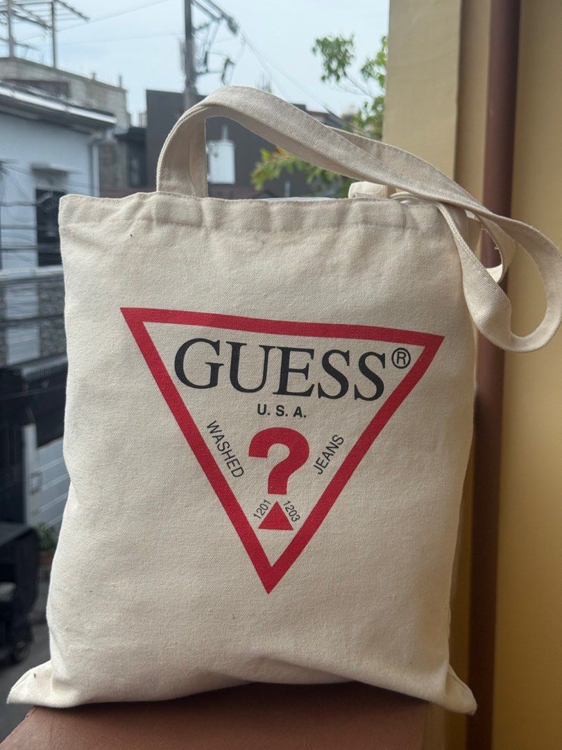 Guess USA Canvas Tote Bag (Category: Tote Bags) located in Paranaque City. Submitted by lyn0618 (Listing ID 1441882198, Image 1). Description: FOR SALE! GUARANTEED AUTHENTIC ! WHITE GUESS TAG INTACT inside SEE PHOTO PROOF it’s ORIGINAL GUESS. NOT COPY. - AUTHENTIC Classic Guess tote bag - Cream canvas with iconic red triangle logo - Small inner pocket with Guess Los Angeles tag - Great for everyday use - Easy to carry PRE LOVED. used. With CARE. 