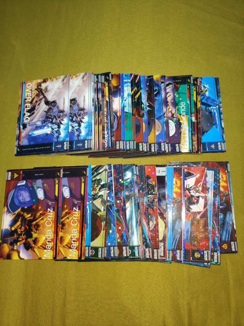 Gundam Trading Cards Collection (Category: Raw Singles) located in Antipolo. Submitted by rllenrapnap (Listing ID 1441915851, Image 1). Description: - Collection of Gundam trading cards - 104 pcs take all bandai - made in japan - Features iconic mobile suits like Over Flag and Zaku - Includes characters such as M'Quve - Perfect for any Gundam enthusiast - Some cards boast holographic effects - All cards are officially from the Gundam series.