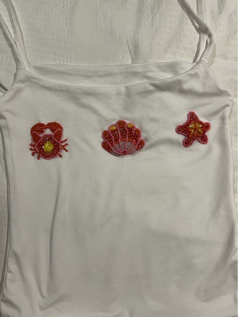 Handmade Beaded Beach Design White Tank Top (Size M) (Category: Sleeveless) located in Quezon City. Submitted by ella.cstn (Listing ID 1441951909, Image 1). Description: Rfs: Prefer diff design - STEAL PRICE!! Got this custom made on ig pa, took 2 months to receive 😭 - Size S-M (my dim: 27wl 32B) - Thick & Stretchy fabric - Minimal flaw (used once) - Beaded Design of Crab🦀, Starfish⭐️, and Shell 🐚 in a pretty 🌺 color palette - Negotiable Pric